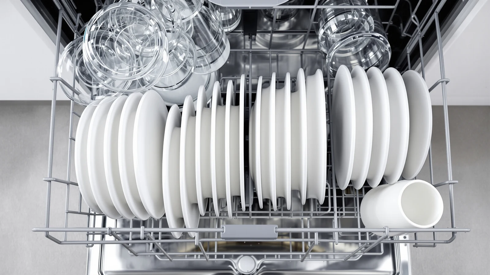 Overhead view of a compact countertop dishwasher's lower rack, plates angled toward the center and bowls turned downward around the spray arm